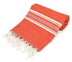 an orange and white blanket with fringes on it's ends, laying flat