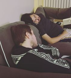 two people are laying on a couch with their eyes closed