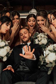 a group of bridesmaids and groomsmid posing for a photo with their hands in the air