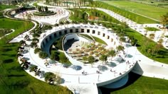 an aerial view of a circular building in the middle of a park with trees and grass