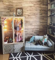 a cat sitting on top of a couch next to a cabinet filled with stuffed animals