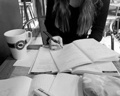 a woman sitting at a table writing in a notebook