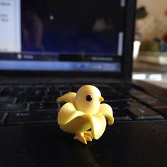 a yellow toy sitting on top of a laptop computer