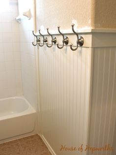 a bathroom with a white tub and four hooks on the wall