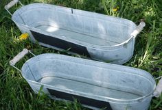 two metal tubs sitting in the grass