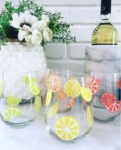 three wine glasses with lemons and lime slices on them next to a bottle of wine