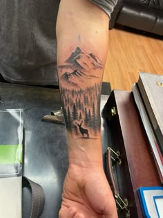 Buck silhouette standing amongst a forest with soaring mountains overlooking. Mountain Men Tattoo, Forearm Landscape Tattoo, Men Tattoo Ideas Hunting, Mountain And Deer Tattoo, Elk With Mountains Tattoo, Sun Mountain Tree Land Water Tattoo, Mens Outdoors Tattoo Ideas, Cool Nature Tattoos For Guys, Elk Tattoo Men Forearm