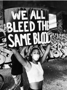 a woman holding up a sign that says we all bleed the same blob