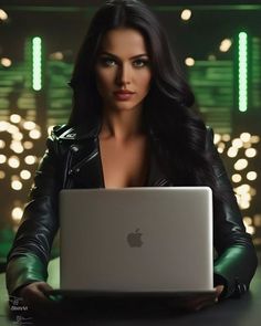 a woman sitting at a table with a laptop in front of her and lights behind her