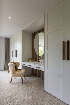 a chair sitting in front of a mirror on top of a white dresser next to a closet