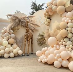 a giraffe is standing next to balloons and palm trees