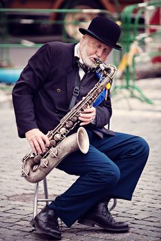 an old man sitting on a chair playing a saxophone