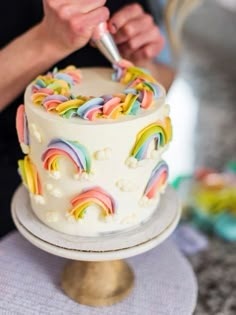 someone is cutting into a cake with rainbows on it