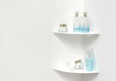 two white shelves with soap and lotion bottles on them, against a white wall