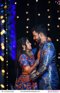 a man and woman standing next to each other in front of some lights at night