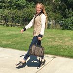 a woman walking down the sidewalk with her suitcase in hand and smiling at the camera