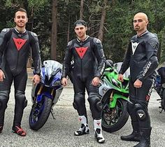 three men in wetsuits stand next to their motorcycles and pose for the camera