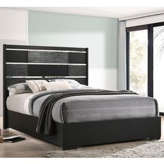 a bed with black headboard and foot board next to a sliding glass door window