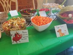 a table topped with lots of food and desserts on top of green cloth covered tables