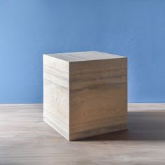 a square wooden object sitting on top of a hard wood floor next to a blue wall