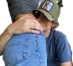 a person wearing a hat and jeans is hugging another person