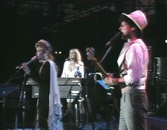 a man standing next to a woman on top of a stage in front of microphones