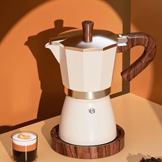 an espresso maker sitting on top of a table next to some coffee beans