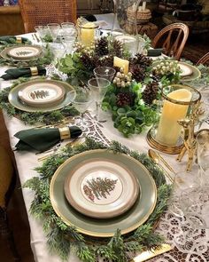 the table is set for christmas dinner with pine cones and greenery