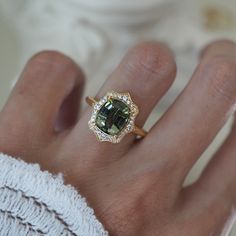 a woman's hand with a ring on it and a green stone in the middle