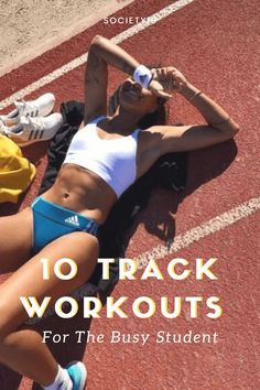 a woman laying on the ground with her arms behind her head and legs crossed, in front of a running track