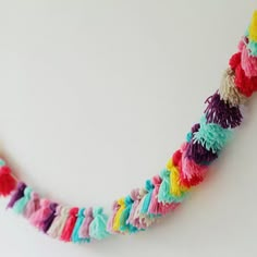 a multicolored necklace with tassels hanging from it's side on a white surface