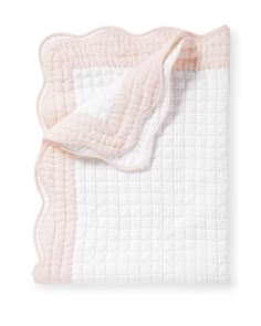 the pink and white blanket is folded on top of an unmade quilted sheet