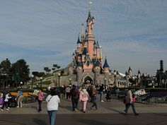 many people are walking around in front of the castle at disneyland world's magic kingdom