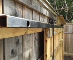 a horse is standing next to a wooden fence with metal bars on it's sides