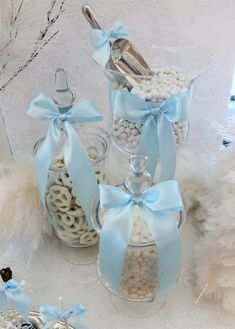 three glass containers filled with candy and candies on top of a white tablecloth