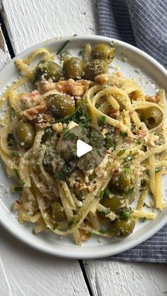 a white plate topped with pasta and olives