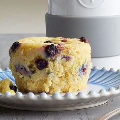 a blueberry muffin on a plate next to a cup