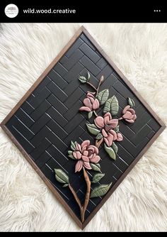 a black and brown tile with pink flowers on the bottom, and green leaves on the top