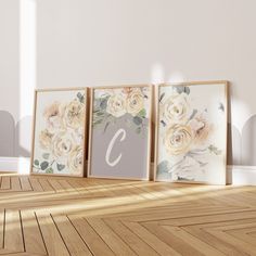 three framed flowers are on the floor in front of a white wall and wooden floors