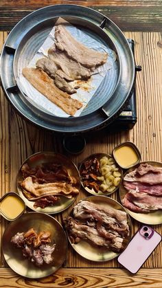 an assortment of meats and sauces in bowls on top of a wooden table