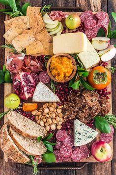 an assortment of cheeses, meats and vegetables on a cutting board with crackers