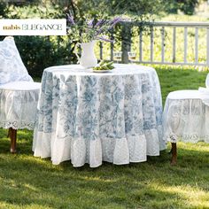 a table with two chairs and a white vase on it in the middle of some grass