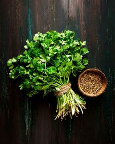 a bunch of green vegetables sitting on top of a wooden table next to a bowl