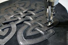 a close up of a sewing machine on a piece of black material with silver letters