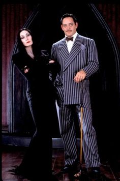 the man and woman are dressed up in black and white striped suits, standing next to each other