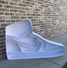 a white sculpture sitting on the side of a brick building