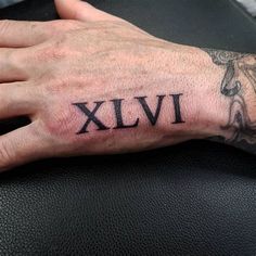 a man's hand with a roman numeral tattoo on it that reads xivi