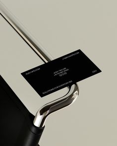 a black and white business card attached to a metal handle on an upright object with a silver bar