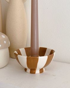 a candle sits in a bowl next to two vases and a mushroom on a shelf