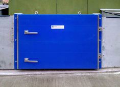 a large blue metal box sitting on the side of a road next to a building